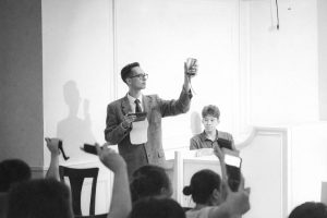 En auktionist håller upp ett föremål inför en publik under en auktion.